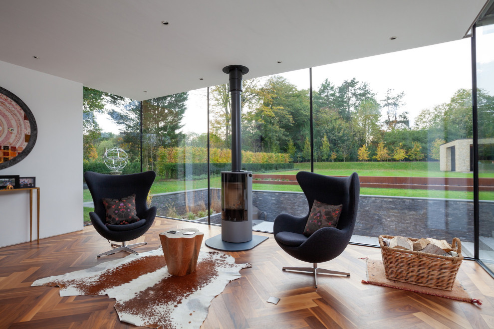 Foto di un soggiorno minimalista con pareti bianche, parquet scuro, stufa a legna e pavimento marrone