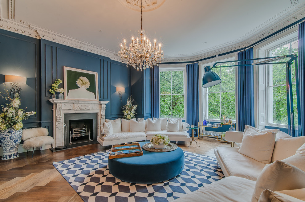 Идея дизайна: огромная открытая гостиная комната в классическом стиле с синими стенами, стандартным камином, фасадом камина из камня, паркетным полом среднего тона и синими шторами без телевизора