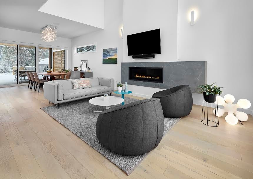 Inspiration for a large modern formal open plan living room in Calgary with white walls, light hardwood flooring, a ribbon fireplace, a stone fireplace surround, a wall mounted tv and brown floors.