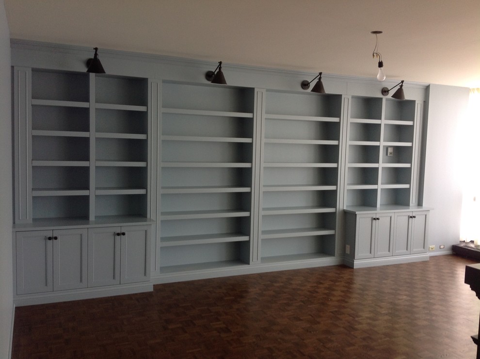 Foto de biblioteca en casa cerrada tradicional de tamaño medio con paredes azules y suelo de madera en tonos medios