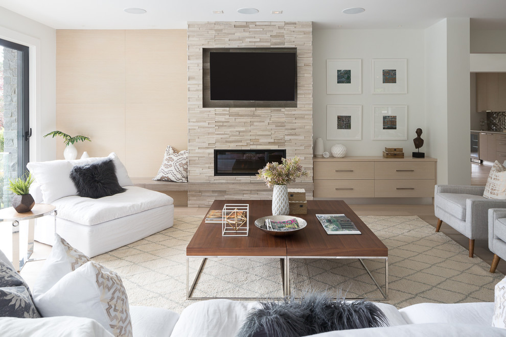 Exempel på ett stort modernt allrum med öppen planlösning, med ljust trägolv, en spiselkrans i sten, en väggmonterad TV, ett finrum, vita väggar, en bred öppen spis och beiget golv