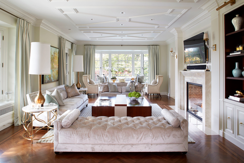 Imagen de salón tradicional con paredes beige, suelo de madera en tonos medios, todas las chimeneas, televisor colgado en la pared y cortinas