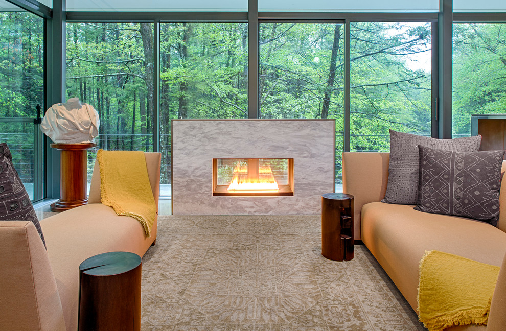 Diseño de salón abierto moderno sin televisor con suelo de cemento, chimenea de doble cara y marco de chimenea de piedra