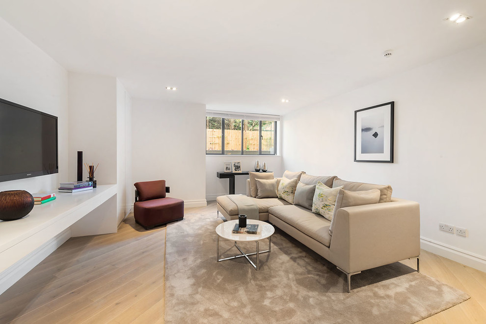 Immagine di un soggiorno minimal con pareti bianche, parquet chiaro e TV a parete