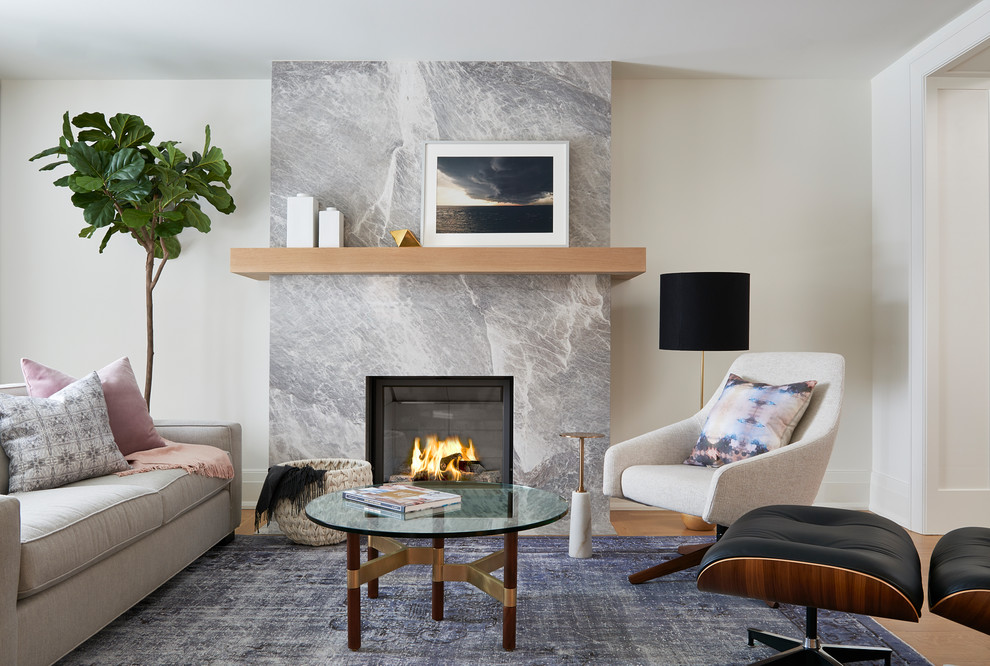 Abgetrenntes Modernes Wohnzimmer mit beiger Wandfarbe, hellem Holzboden, Kamin und Kaminumrandung aus Stein in Toronto