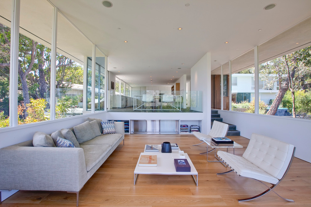 Foto di un soggiorno moderno aperto con pareti bianche e parquet chiaro