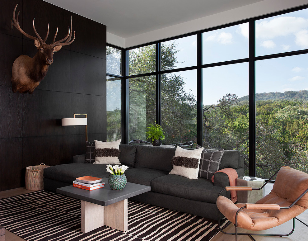 Стильный дизайн: изолированная гостиная комната в стиле модернизм с черными стенами и светлым паркетным полом - последний тренд