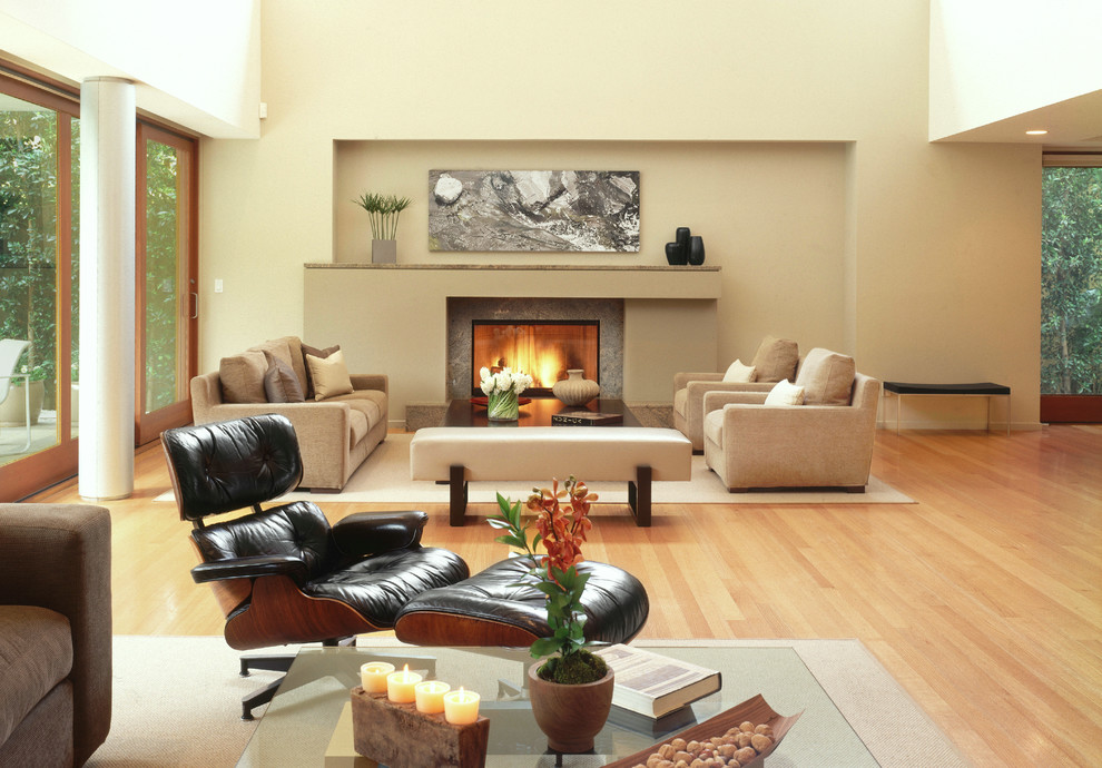 Réalisation d'un grand salon design ouvert avec un mur beige, parquet clair, une cheminée standard et un manteau de cheminée en pierre.