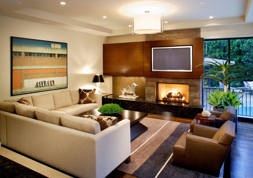 Großes, Offenes Modernes Wohnzimmer mit Kamin, TV-Wand, beiger Wandfarbe, dunklem Holzboden und Kaminumrandung aus Stein in Miami