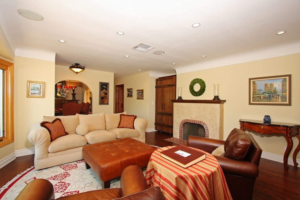 Fernseherloses, Offenes Klassisches Wohnzimmer mit beiger Wandfarbe, dunklem Holzboden und Kamin in Los Angeles