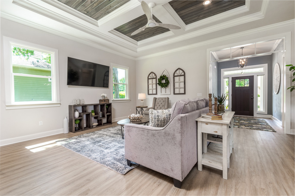 French country open concept light wood floor, beige floor and vaulted ceiling living room photo in Other with gray walls and a wall-mounted tv
