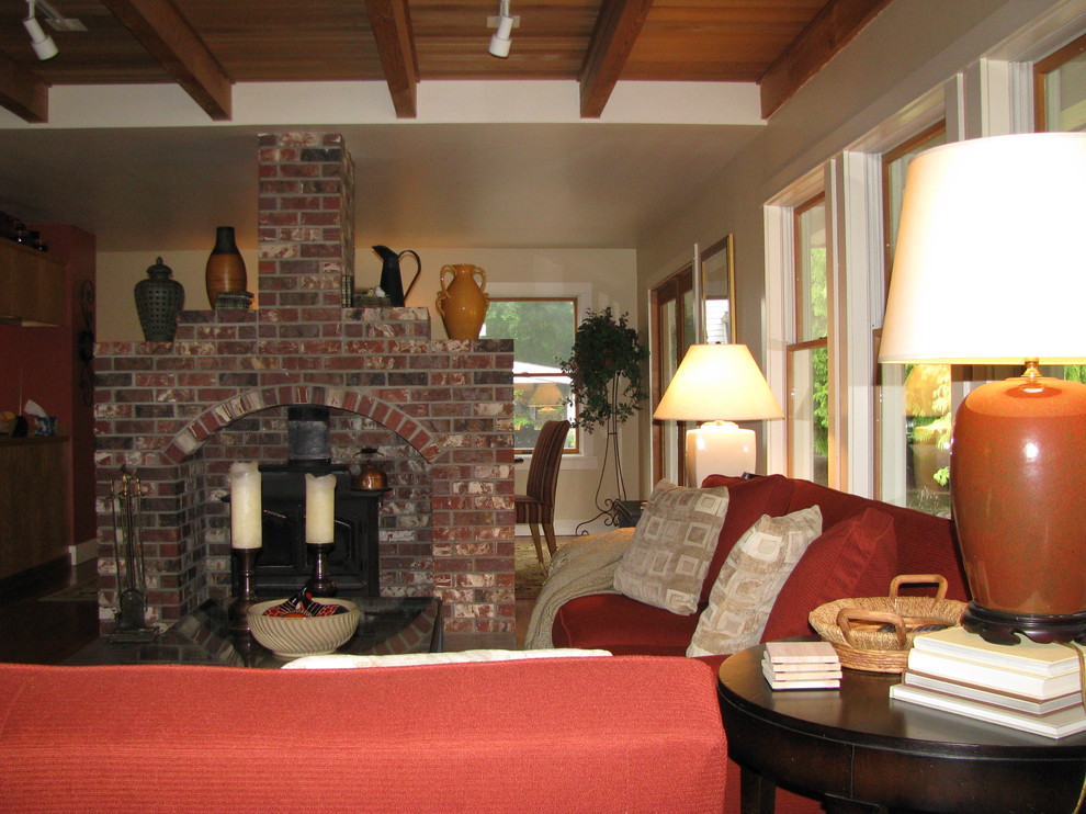 Ejemplo de salón abierto tradicional renovado con paredes amarillas, suelo de madera clara, chimenea de doble cara, marco de chimenea de ladrillo y televisor retractable
