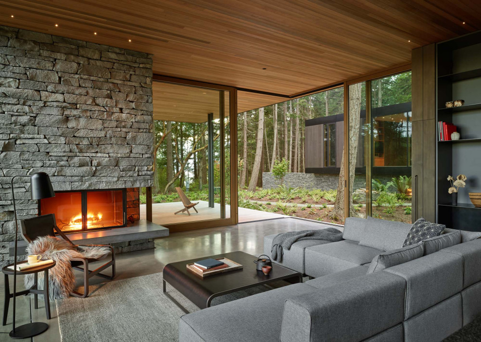 Offenes Modernes Wohnzimmer mit Betonboden, Kamin, Kaminumrandung aus gestapelten Steinen, grauem Boden und Holzdecke in Seattle