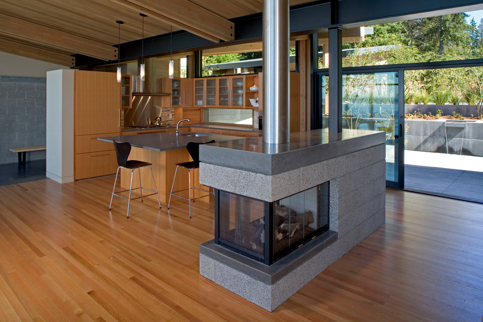 Inspiration pour un salon design ouvert avec parquet clair, une cheminée double-face et un manteau de cheminée en béton.