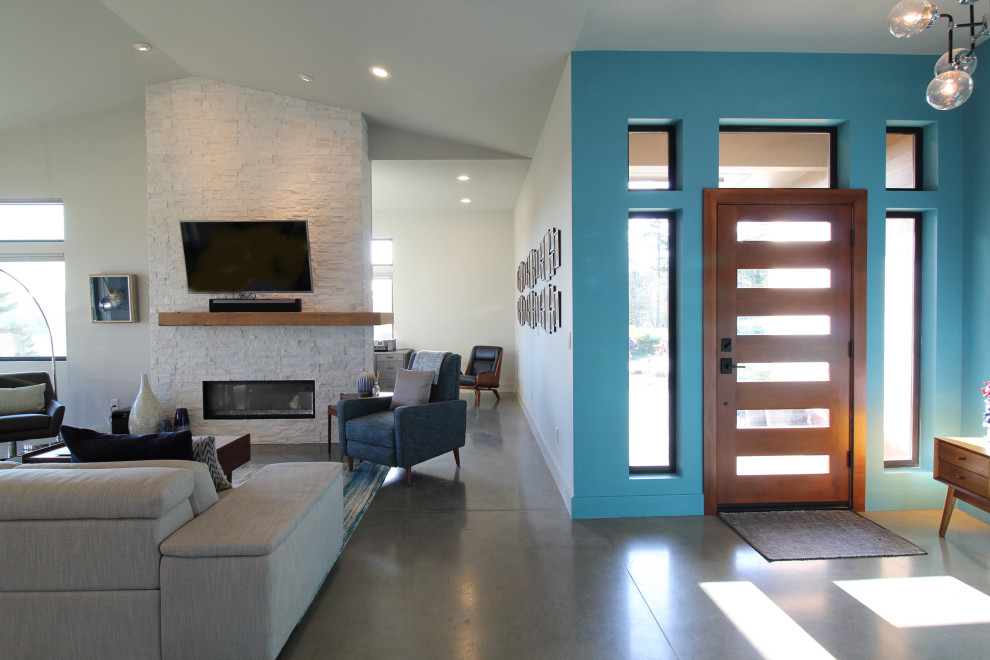 На фото: открытая гостиная комната среднего размера в стиле ретро с серыми стенами, бетонным полом, двусторонним камином, фасадом камина из каменной кладки, телевизором на стене, серым полом и сводчатым потолком с