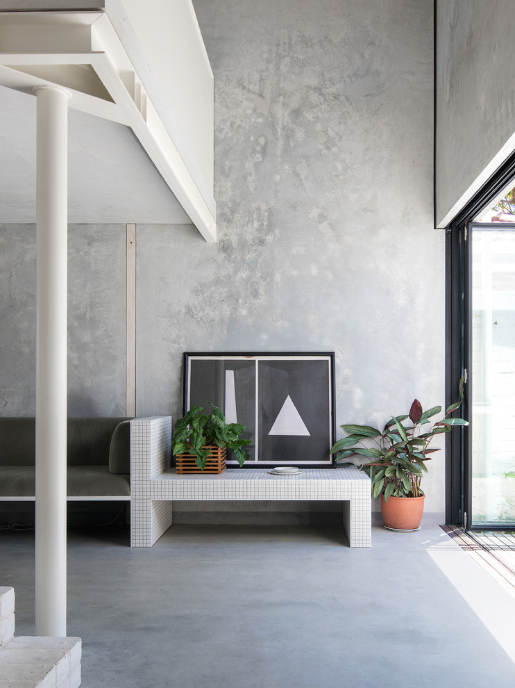 Diseño de salón abierto industrial sin chimenea con paredes grises, suelo de cemento y suelo gris
