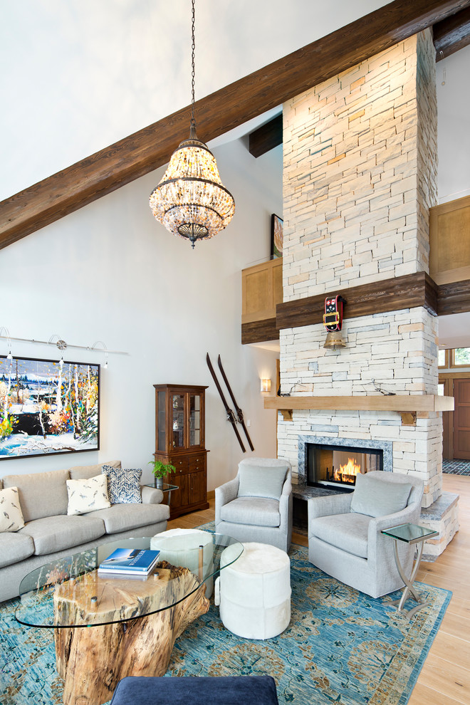 Mountain style loft-style light wood floor and beige floor living room photo in Vancouver with gray walls, a two-sided fireplace and a stone fireplace