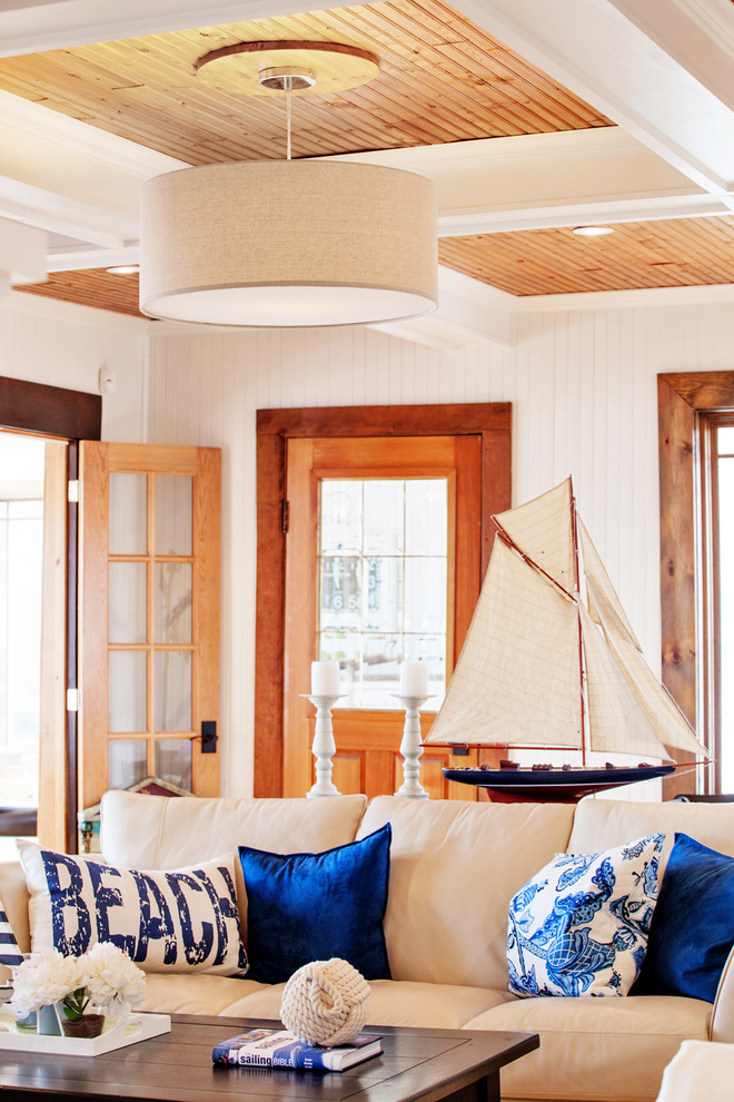 Cette photo montre un salon bord de mer de taille moyenne et fermé avec une bibliothèque ou un coin lecture, un mur blanc, parquet clair, une cheminée standard, un manteau de cheminée en bois et un téléviseur encastré.