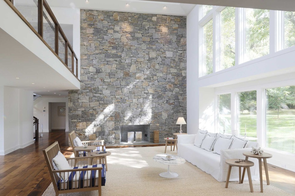 На фото: большая открытая гостиная комната в современном стиле с стандартным камином, фасадом камина из камня, белыми стенами и паркетным полом среднего тона без телевизора с