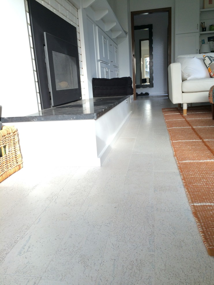 Esempio di un soggiorno minimal di medie dimensioni e chiuso con pareti bianche, pavimento in sughero, camino classico e cornice del camino in mattoni