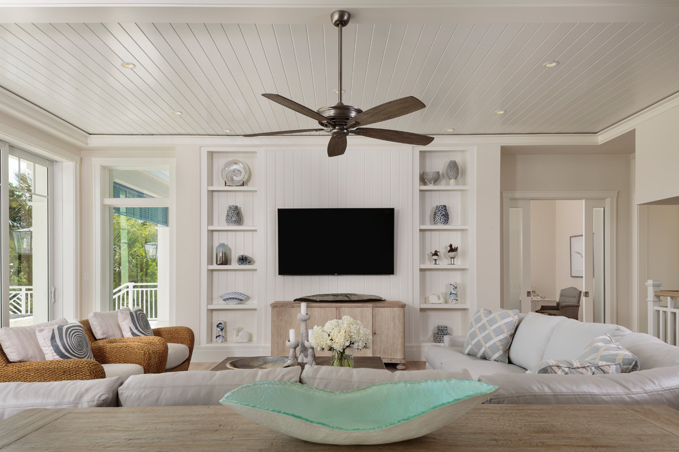 Mid-sized island style open concept light wood floor and brown floor living room photo in Miami with white walls and a media wall