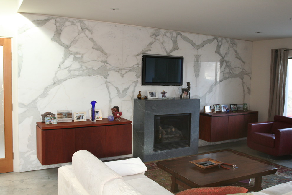 Mid-sized trendy open concept concrete floor living room photo in Santa Barbara with white walls, a standard fireplace, a stone fireplace and a wall-mounted tv