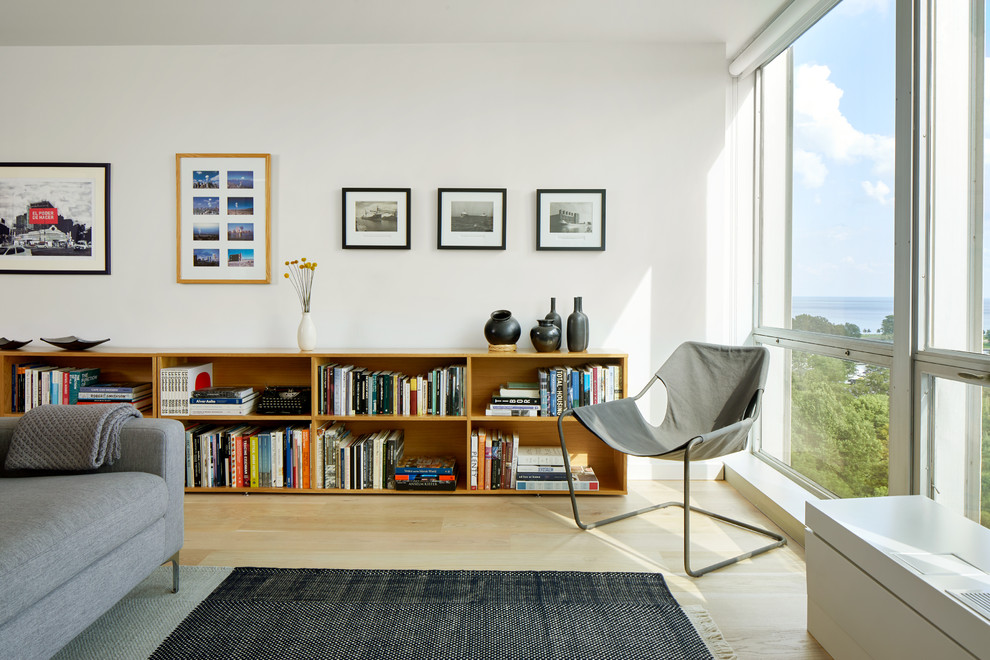 Aménagement d'un salon scandinave ouvert et de taille moyenne avec un mur blanc, parquet clair, une bibliothèque ou un coin lecture et un sol marron.