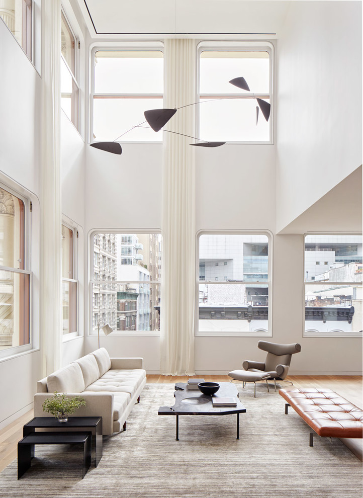 Modern open plan living room in New York with white walls, medium hardwood flooring and brown floors.