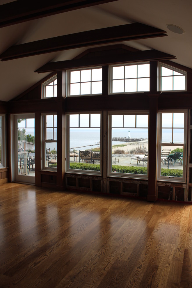 Cette image montre un salon marin ouvert avec un sol en bois brun.
