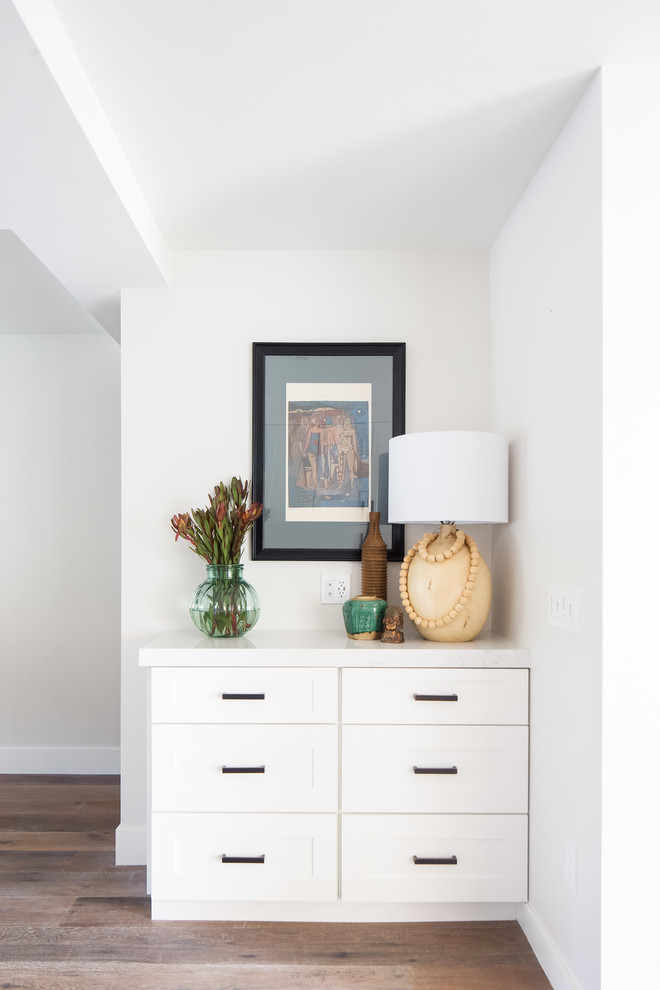 Источник вдохновения для домашнего уюта: открытая гостиная комната среднего размера в стиле неоклассика (современная классика) с белыми стенами, паркетным полом среднего тона, стандартным камином, фасадом камина из плитки, телевизором на стене и коричневым полом