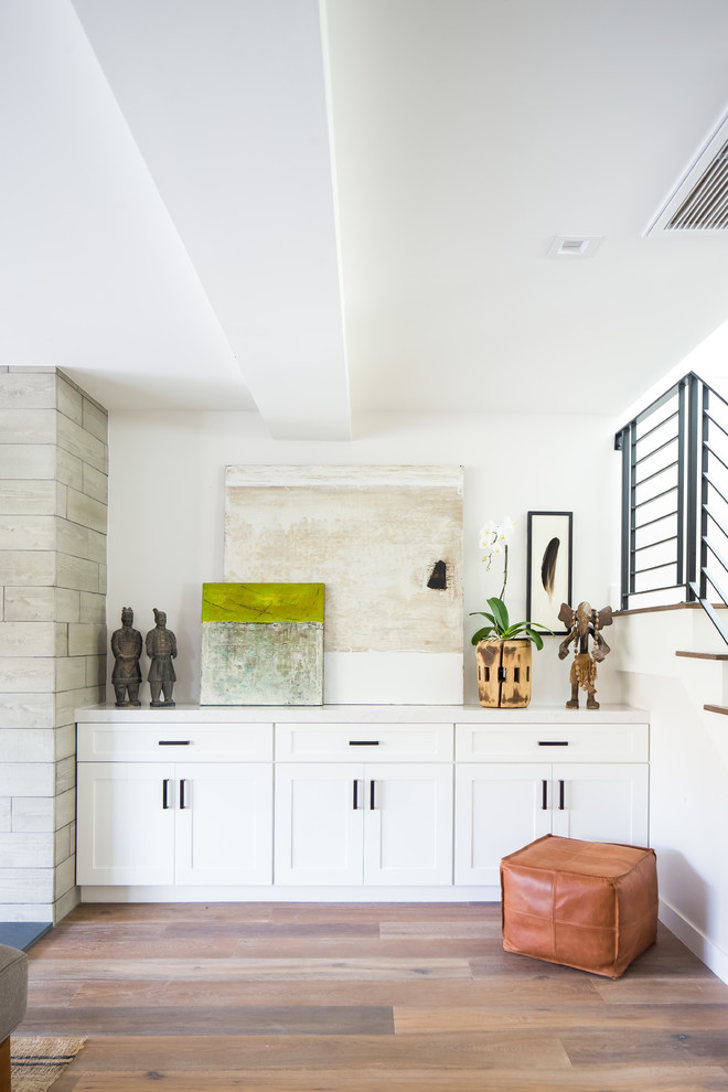 Идея дизайна: открытая гостиная комната среднего размера в стиле неоклассика (современная классика) с белыми стенами, паркетным полом среднего тона, стандартным камином, фасадом камина из плитки, телевизором на стене и коричневым полом