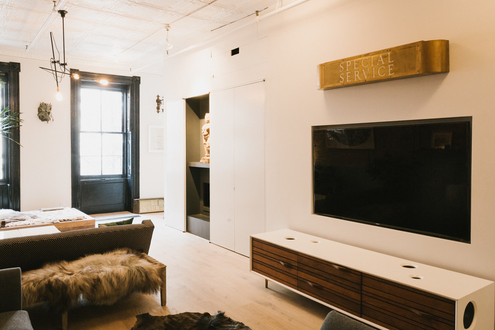 Пример оригинального дизайна: двухуровневая гостиная комната среднего размера в современном стиле с светлым паркетным полом, телевизором на стене, стандартным камином, фасадом камина из камня и белыми стенами