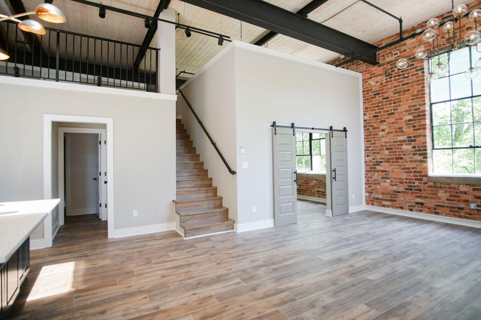 This is an example of a medium sized urban mezzanine living room in Atlanta with vinyl flooring, no fireplace, brown floors, exposed beams and panelled walls.