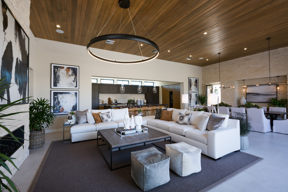 This is an example of a large contemporary open plan living room in Phoenix with beige walls, a ribbon fireplace, a stone fireplace surround and white floors.