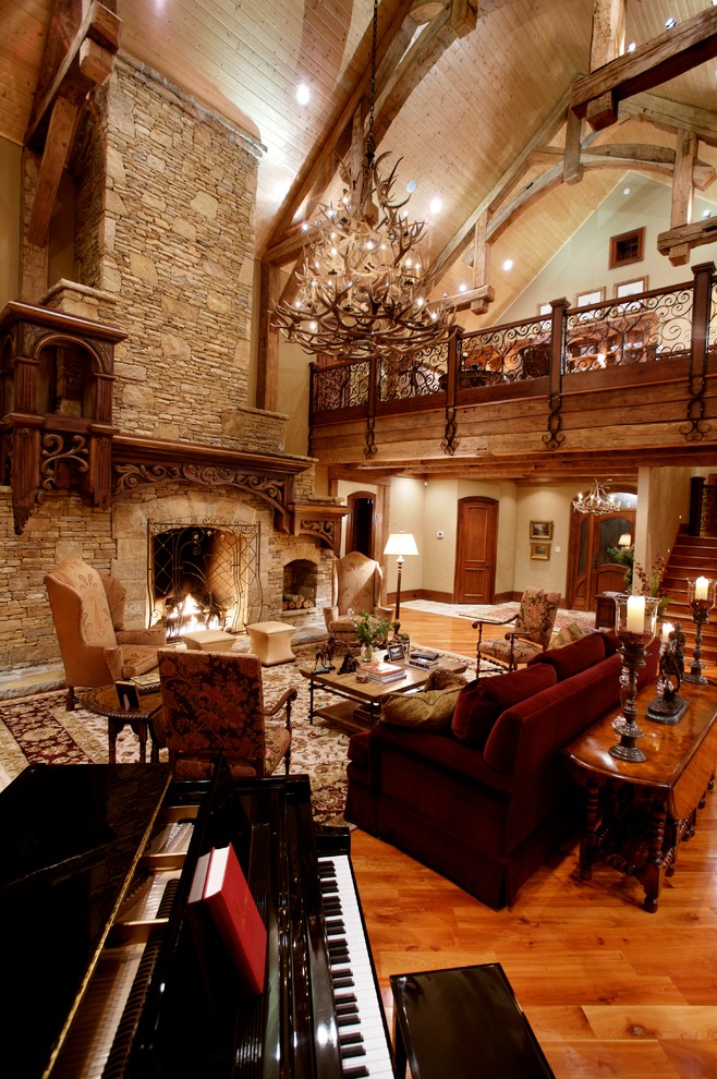 Aménagement d'un très grand salon montagne ouvert avec une salle de réception, un mur beige, un sol en bois brun, une cheminée standard, un manteau de cheminée en pierre et aucun téléviseur.