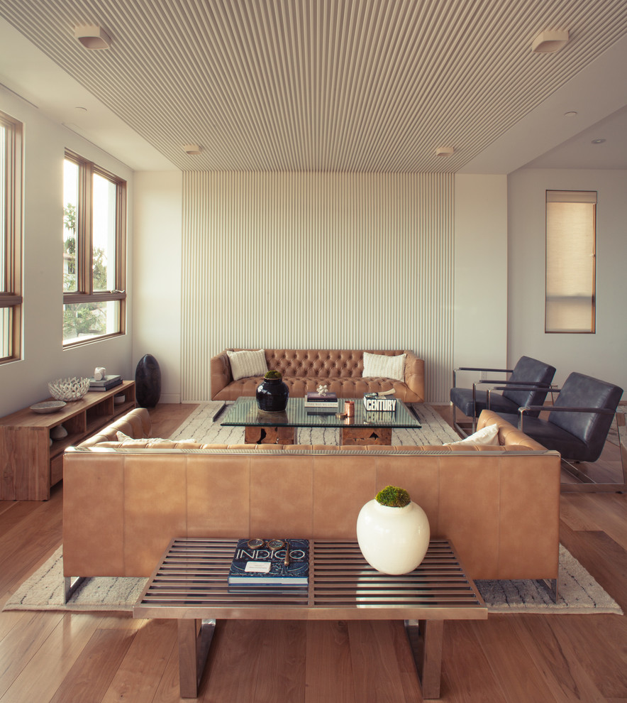 Cette image montre un salon design ouvert avec une salle de réception, un mur blanc et un sol en bois brun.