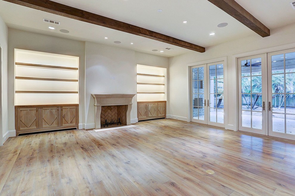 Klassisches Wohnzimmer mit weißer Wandfarbe, hellem Holzboden, Kamin und Kaminumrandung aus Stein in Houston