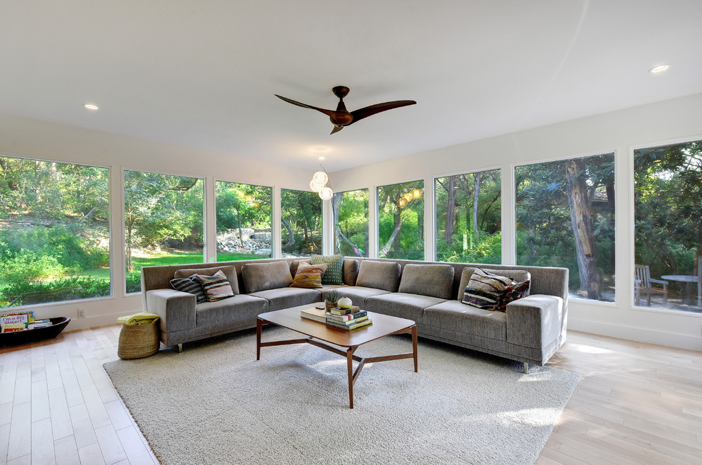 Large midcentury formal open plan living room in Austin with white walls, light hardwood flooring, no fireplace and no tv.