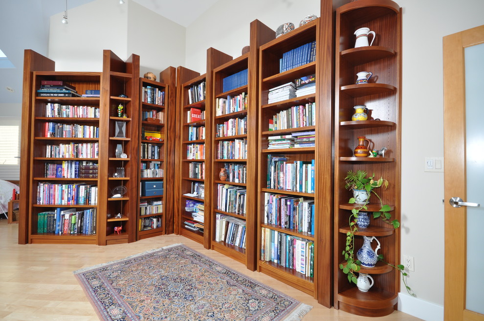 Immagine di un ampio soggiorno minimal aperto con libreria, pareti beige, parquet chiaro, stufa a legna, cornice del camino in pietra e nessuna TV