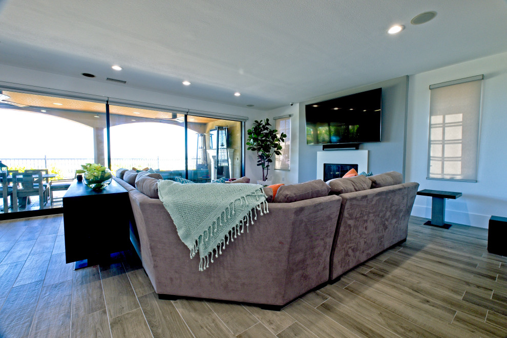 Cette image montre un grand salon minimaliste ouvert avec un mur gris, un sol en carrelage de porcelaine, une cheminée standard et un téléviseur fixé au mur.