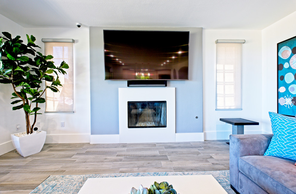 Aménagement d'un grand salon moderne ouvert avec un mur gris, un sol en carrelage de porcelaine, une cheminée standard et un téléviseur fixé au mur.