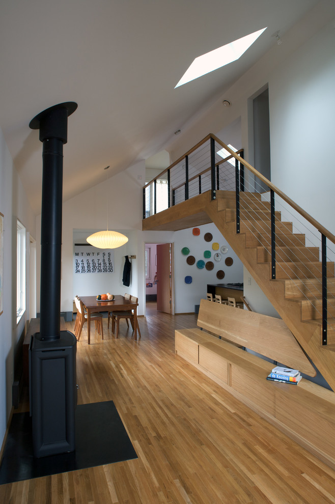 Idée de décoration pour un salon minimaliste ouvert avec un mur blanc, un poêle à bois et un escalier.