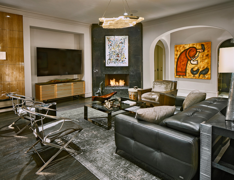 Cette image montre un salon design avec un mur gris, parquet foncé, une cheminée d'angle, un manteau de cheminée en pierre, un sol noir et un téléviseur fixé au mur.