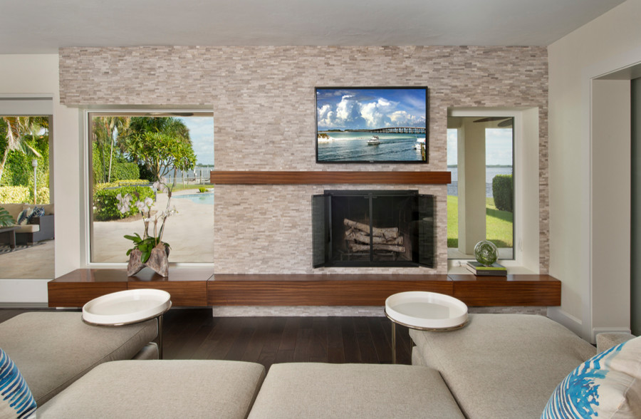 На фото: открытая гостиная комната среднего размера в современном стиле с белыми стенами, темным паркетным полом, стандартным камином, фасадом камина из камня, телевизором на стене и коричневым полом