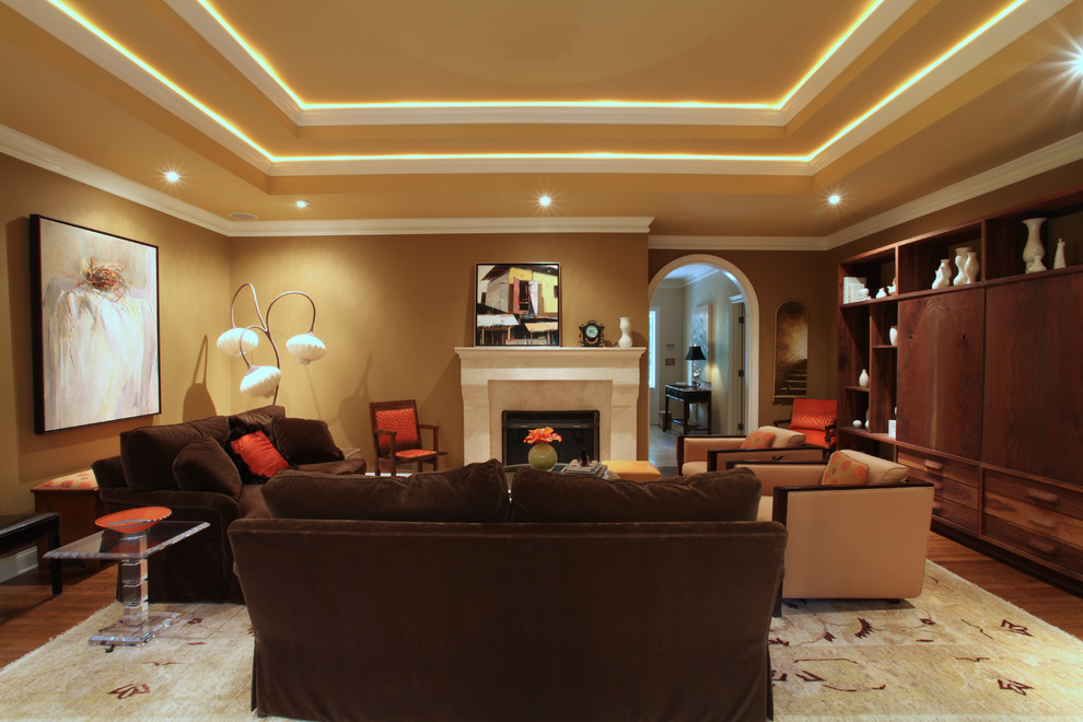 Immagine di un grande soggiorno minimalista chiuso con pareti marroni, pavimento in legno massello medio, camino classico e cornice del camino in pietra