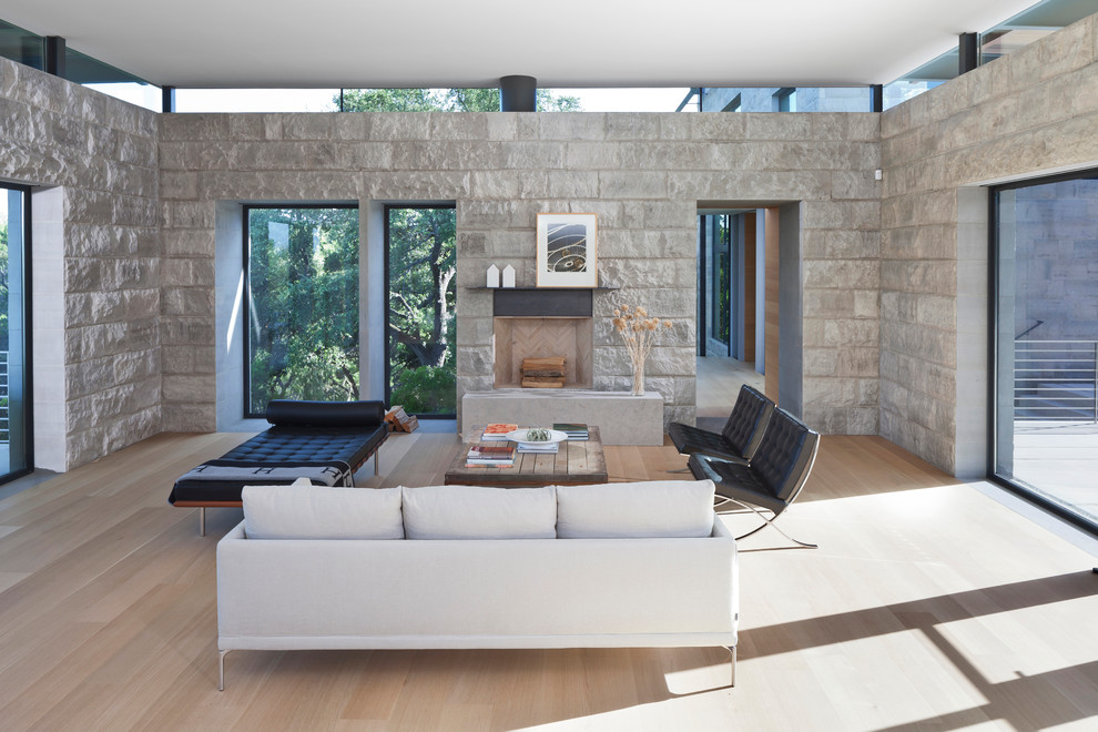 Imagen de salón para visitas abierto contemporáneo grande con paredes beige, suelo de madera clara, todas las chimeneas, marco de chimenea de piedra y televisor independiente