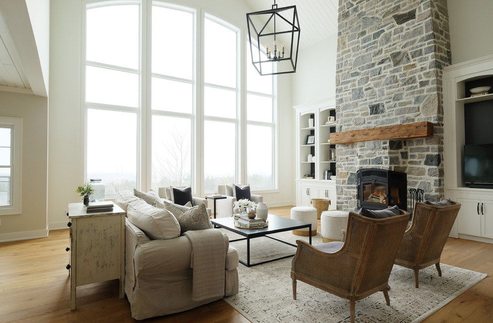 Design ideas for a medium sized rural open plan living room in Other with white walls, medium hardwood flooring, a standard fireplace, a stone fireplace surround, a built-in media unit and brown floors.