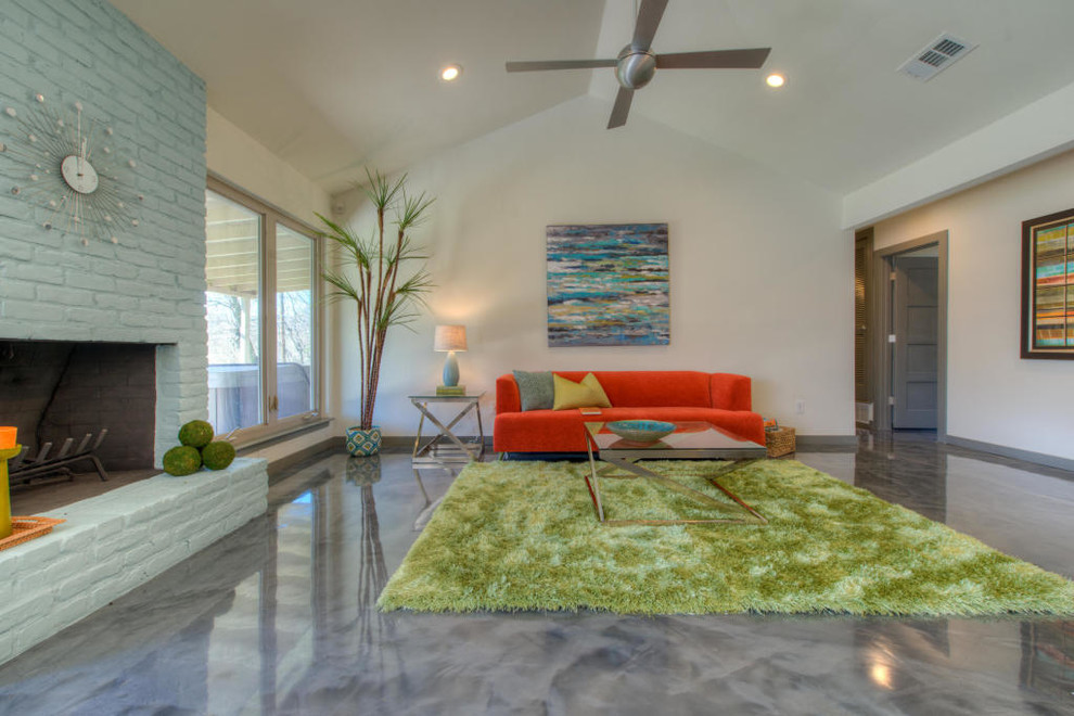 Offenes Retro Wohnzimmer mit weißer Wandfarbe, Betonboden und Kaminumrandung aus Backstein in Austin