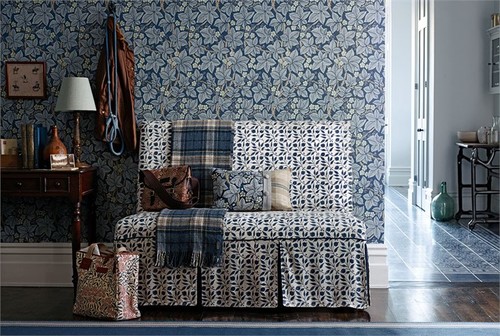 small vintage styled sofa in a blue pattern against a blue floral wallpaper 