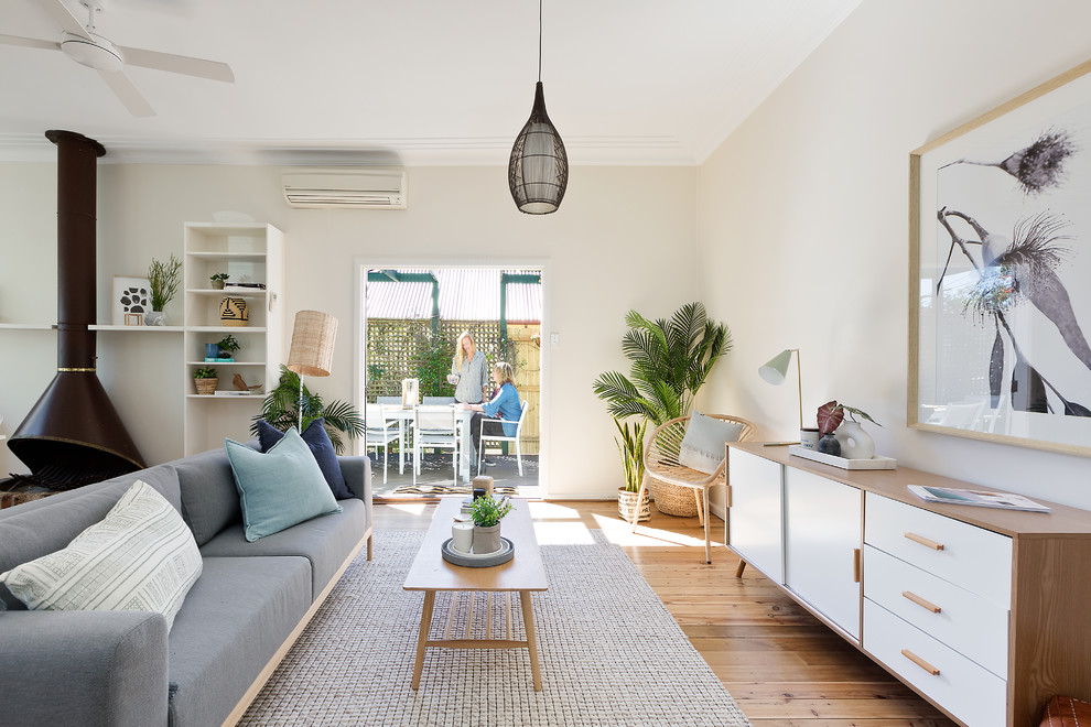 Mittelgroßes, Offenes, Repräsentatives Maritimes Wohnzimmer mit Kaminofen, beiger Wandfarbe, braunem Holzboden und beigem Boden in Sydney